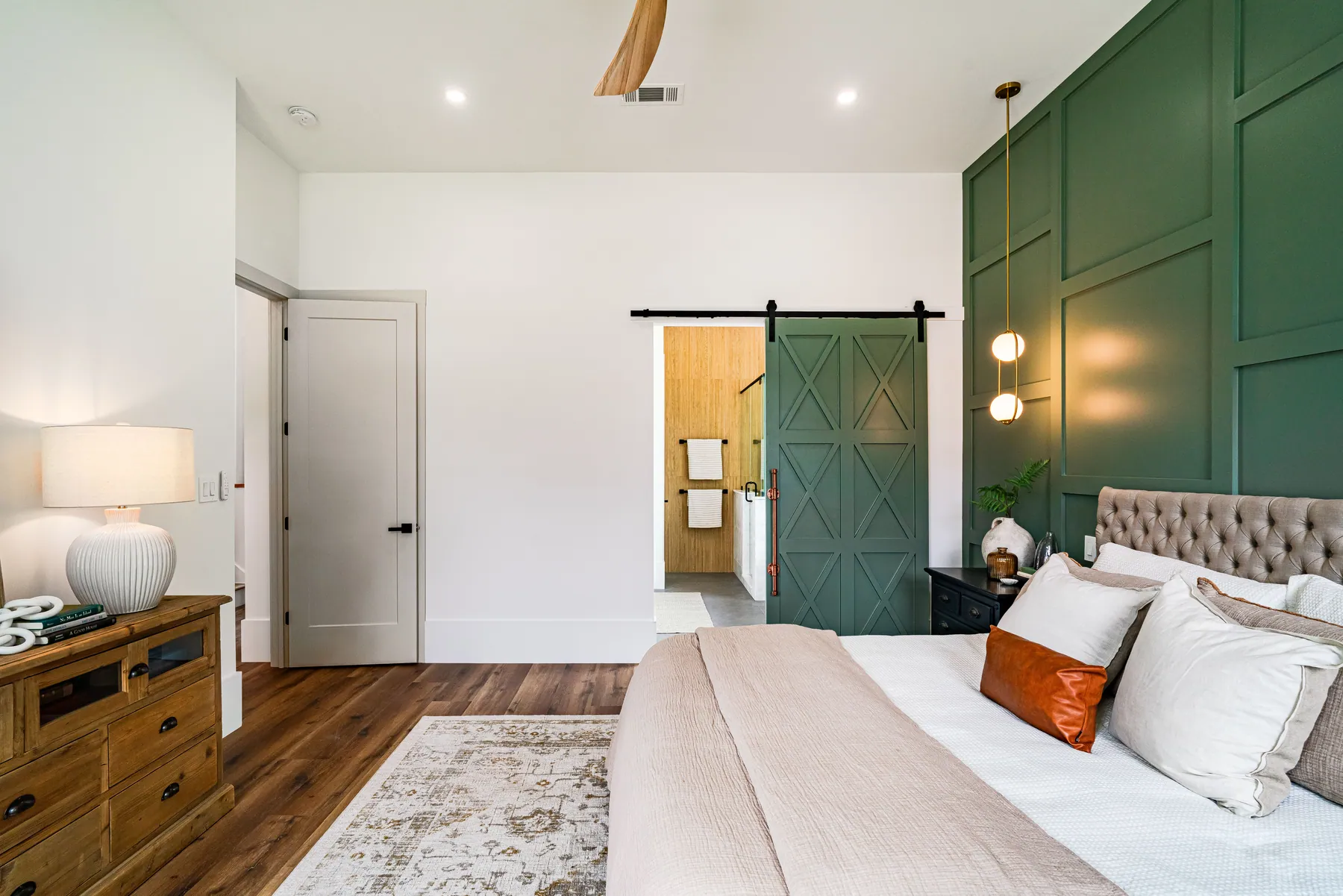Bedroom with a finished green board-and-batten accent wall and matching barn door